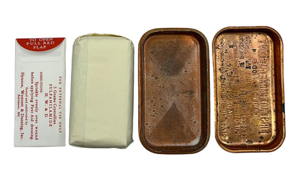 An antique medicine tin set shown on a light gray background, including a red-and-white paper flap on the left, a wrapped cream-colored medicine packet in the middle, and the open copper-toned metal tin with embossed text on the right.