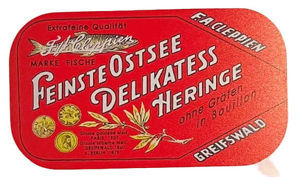 A vintage German fish can label design for 'Feinste Ostsee Delikatess Heringe' by Greifswald, featuring a red rounded rectangle with white lettering and gold fish illustrations on a white background.