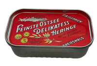 A vintage German tin of Greifswald Ostsee Delikatesse Heringe (cured herring) with a red label and white lettering, set against a plain light background.