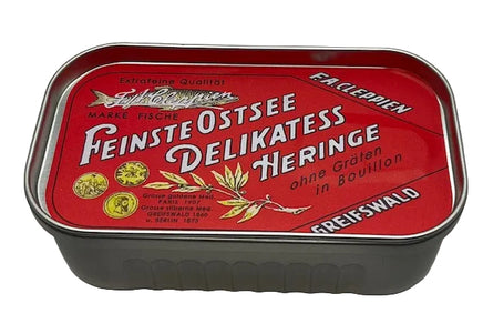 A vintage German tin of Greifswald Ostsee Delikatesse Heringe (cured herring) with a red label and white lettering, set against a plain light background.